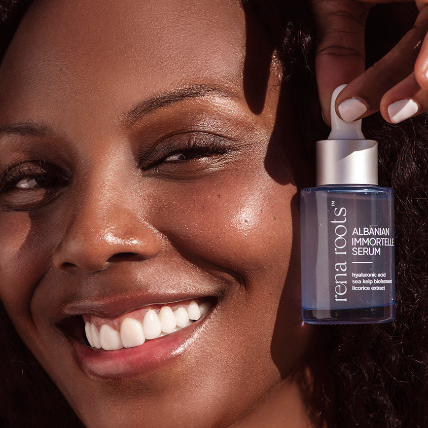 Woman holding a bottle of Rena Roots Albanian Immortelle Serum close to her face