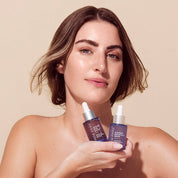 Woman holding two Rena Roots Serums against a beige background