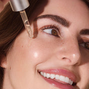 Close-up of a woman applying Rena Roots Afghan Rose Serum to her face.